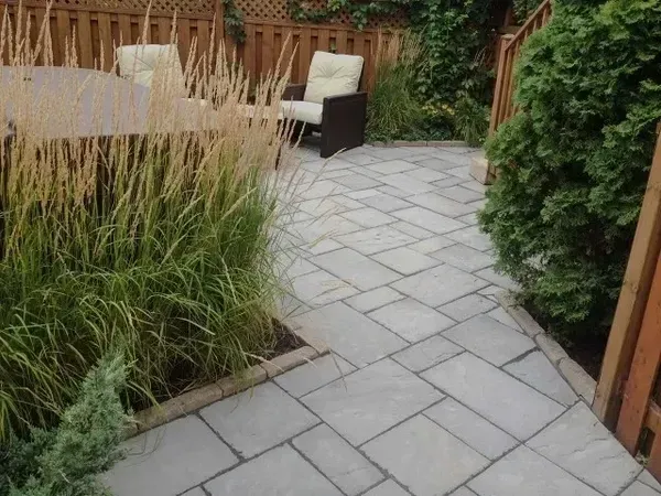 Un patio avec une table et des chaises et une clôture en arrière-plan.