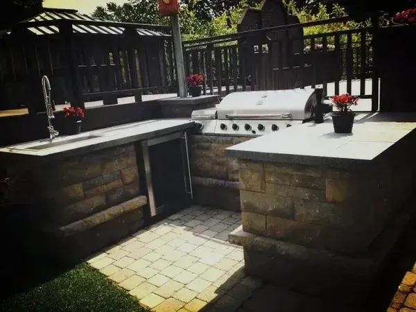 Une cuisine extérieure avec un grill et un évier