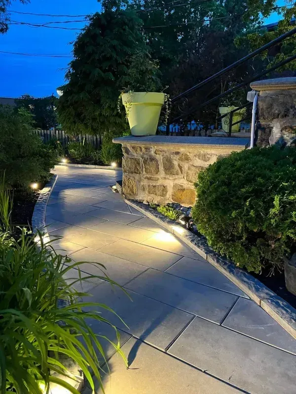 Une allée est éclairée la nuit dans un jardin.