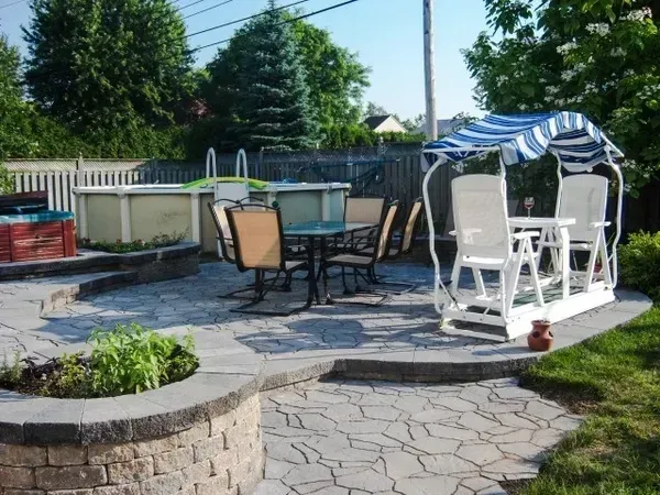 Un patio avec une table et des chaises et une balançoire avec un auvent bleu et blanc