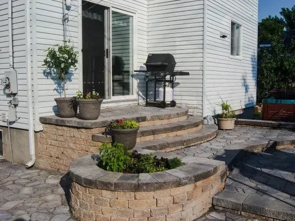 Un patio avec un grill et des plantes en pot devant une maison.