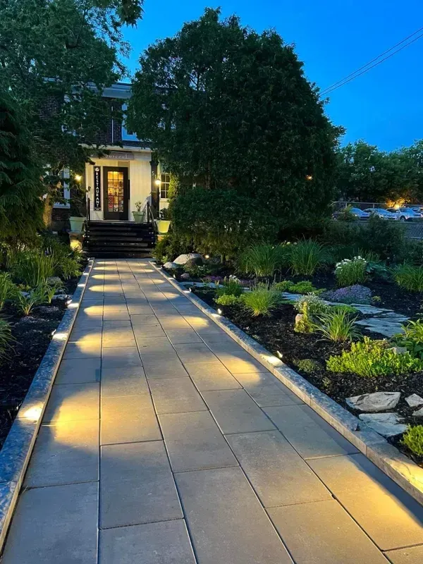 A walkway leading to a house is lit up at night.