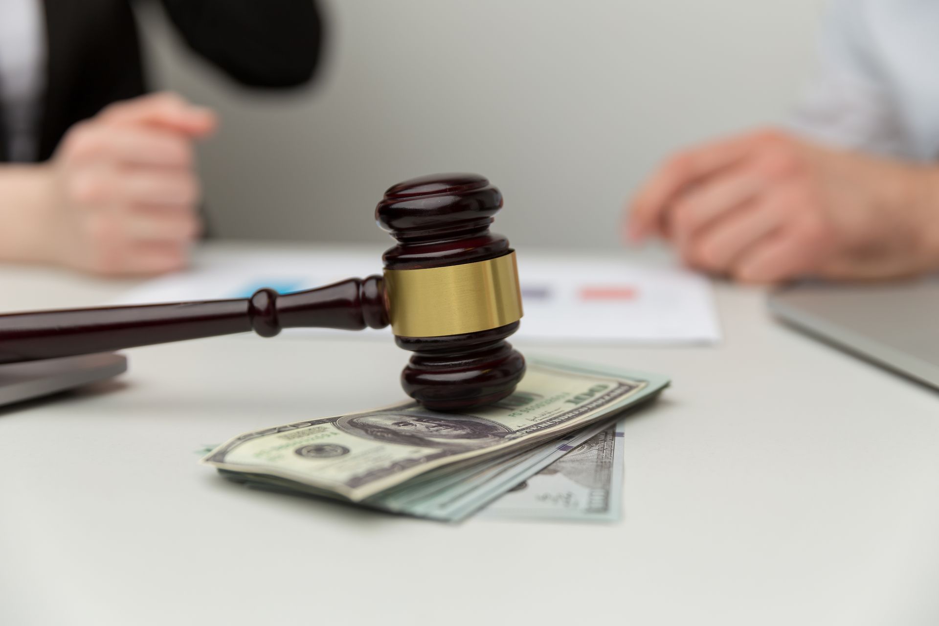 Judge’s gavel resting on a stack of cash on a table during a legal financial discussion.