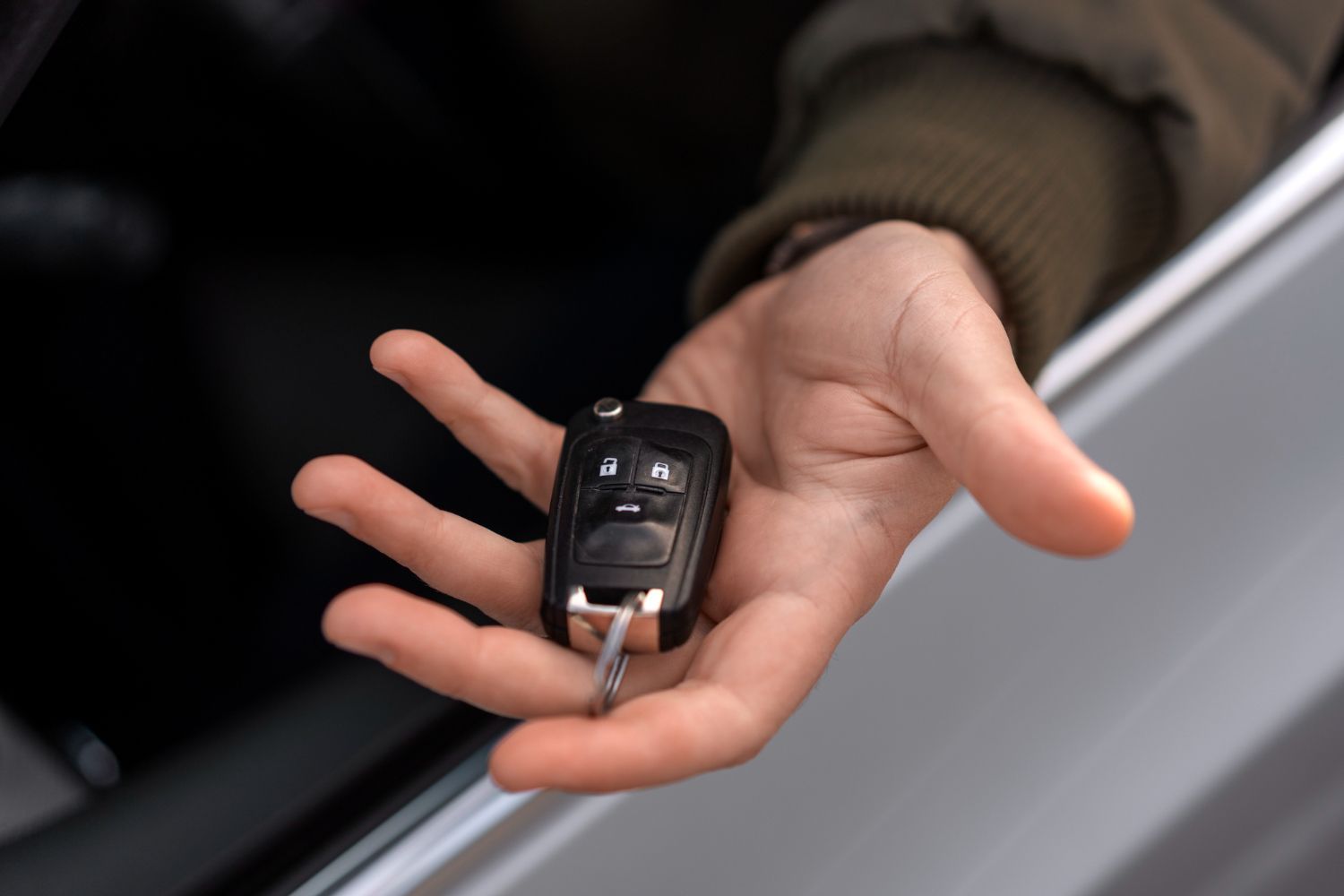 A person is holding a car key in their hand in a car.