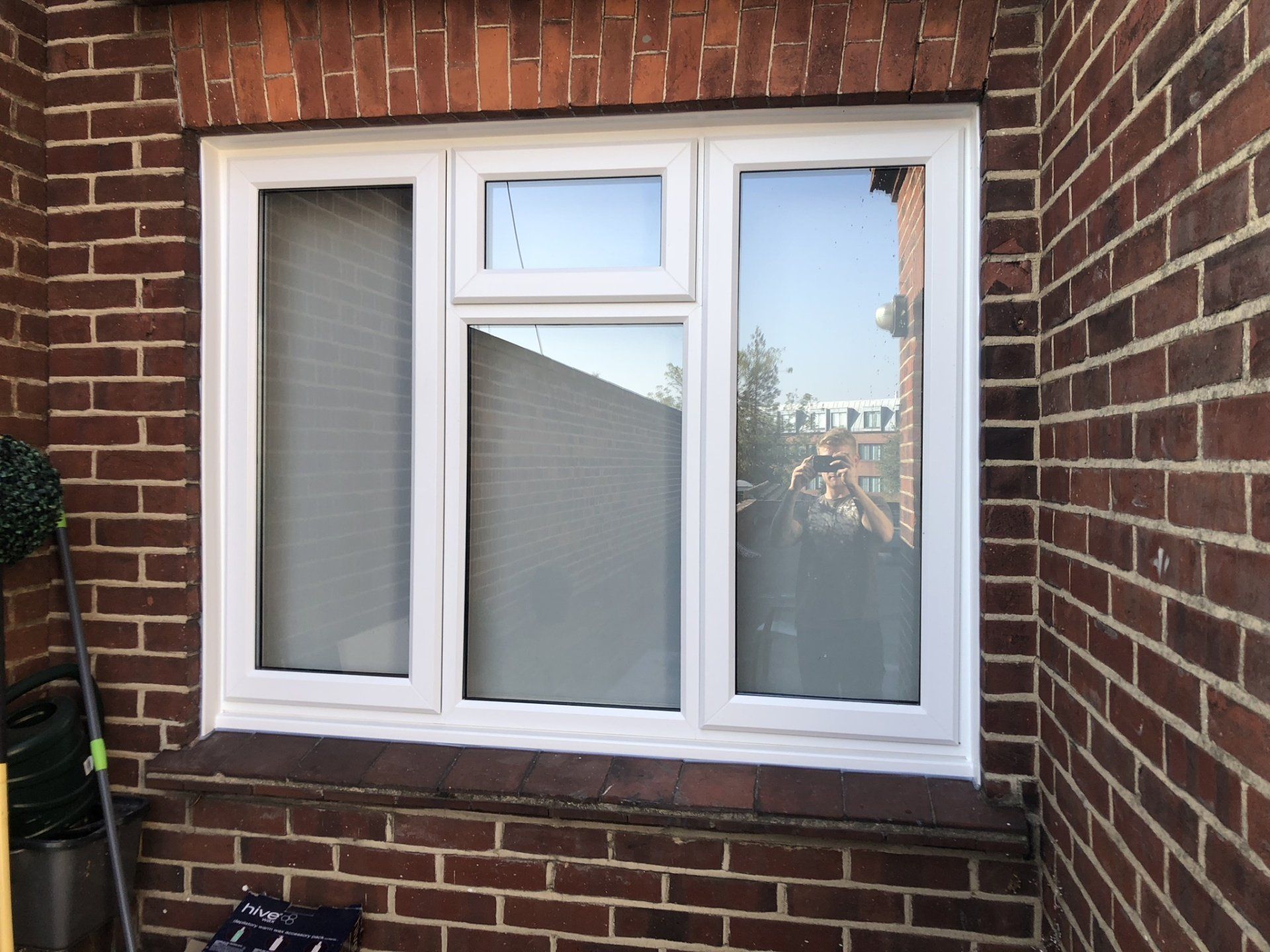 A white window is on the side of a brick building.