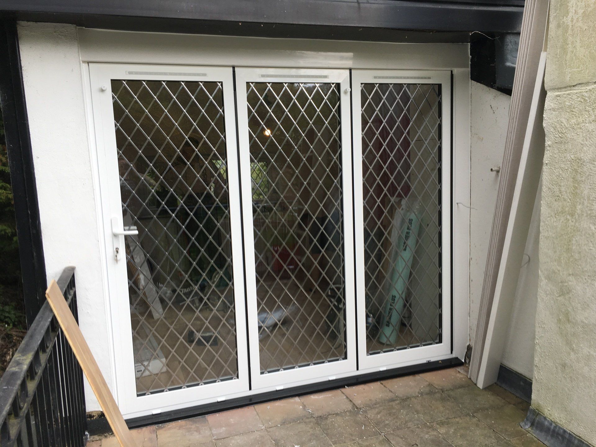 A white door with a diamond pattern on it is sitting on a balcony.
