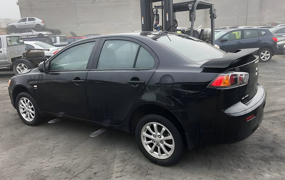 Black Mitsubishi Lancer Sedan Parked in a Junkyard