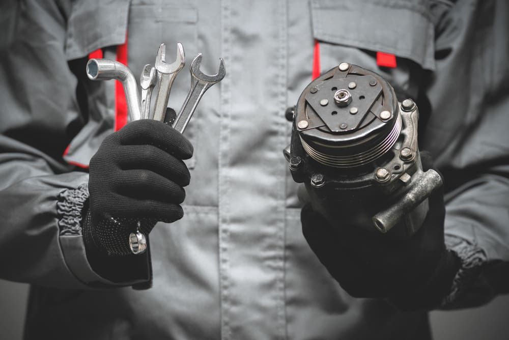 A Mechanic Is Holding A Wrench And A Piece Of Equipment In His Hands — Twin City Auto Dismantlers In Beechworth, VIC