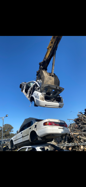 A wrecked car being hoisted in the air.
