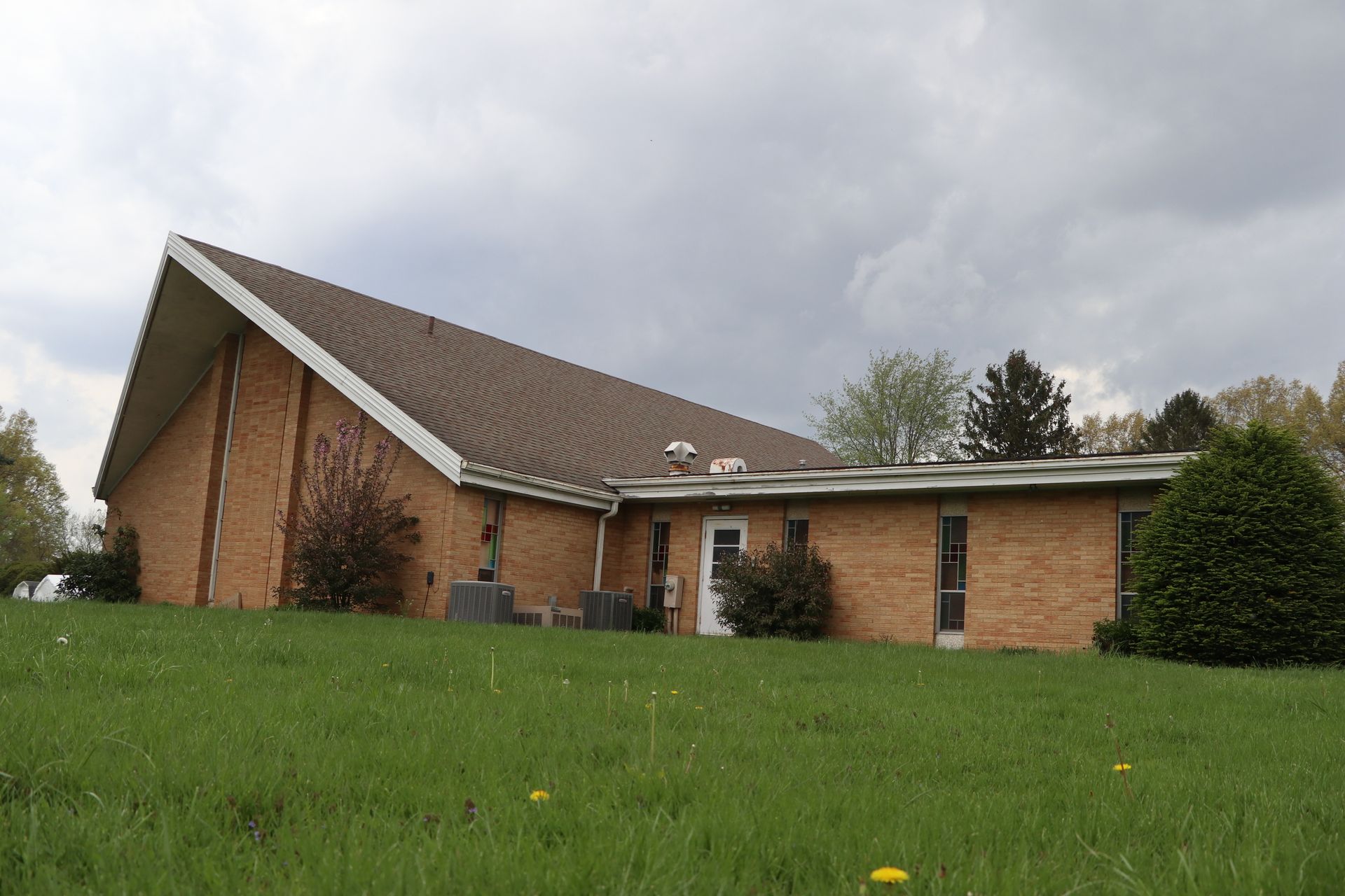 A large brick building is sitting on top of a grassy hill.
