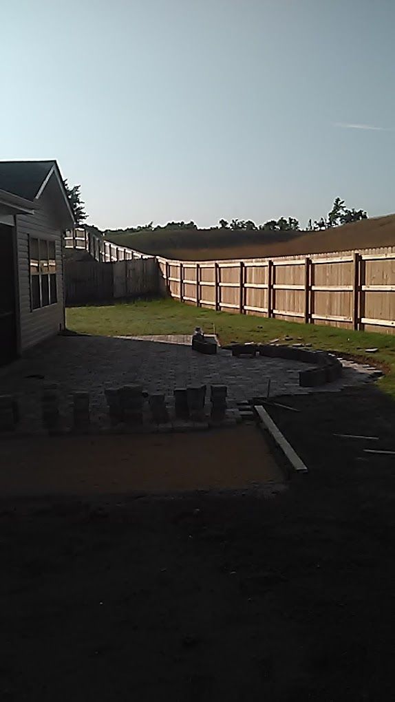 A backyard with a fence and a house in the background.