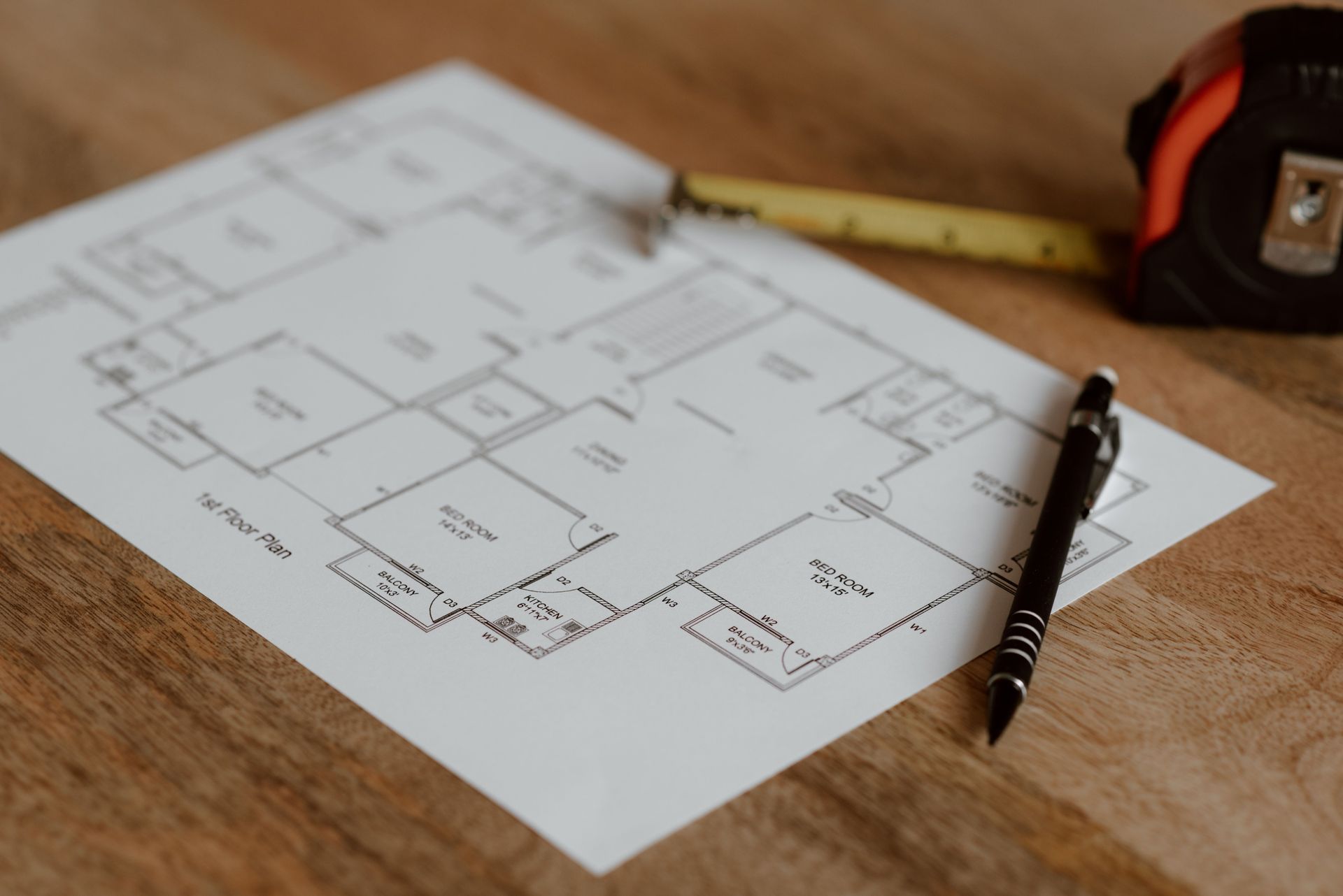 Architectural floor plan on a desk with a pencil and tape measure nearby