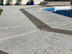 Gray concrete pool deck with a dark pebble border.