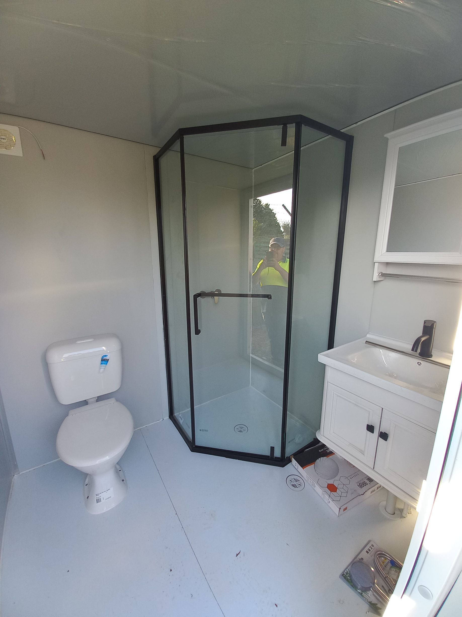 Small bathroom with shower, toilet, and vanity. Gray walls, white floor, and a window  — Tenterfield Timber & Hardware in Tenterfield, NSW