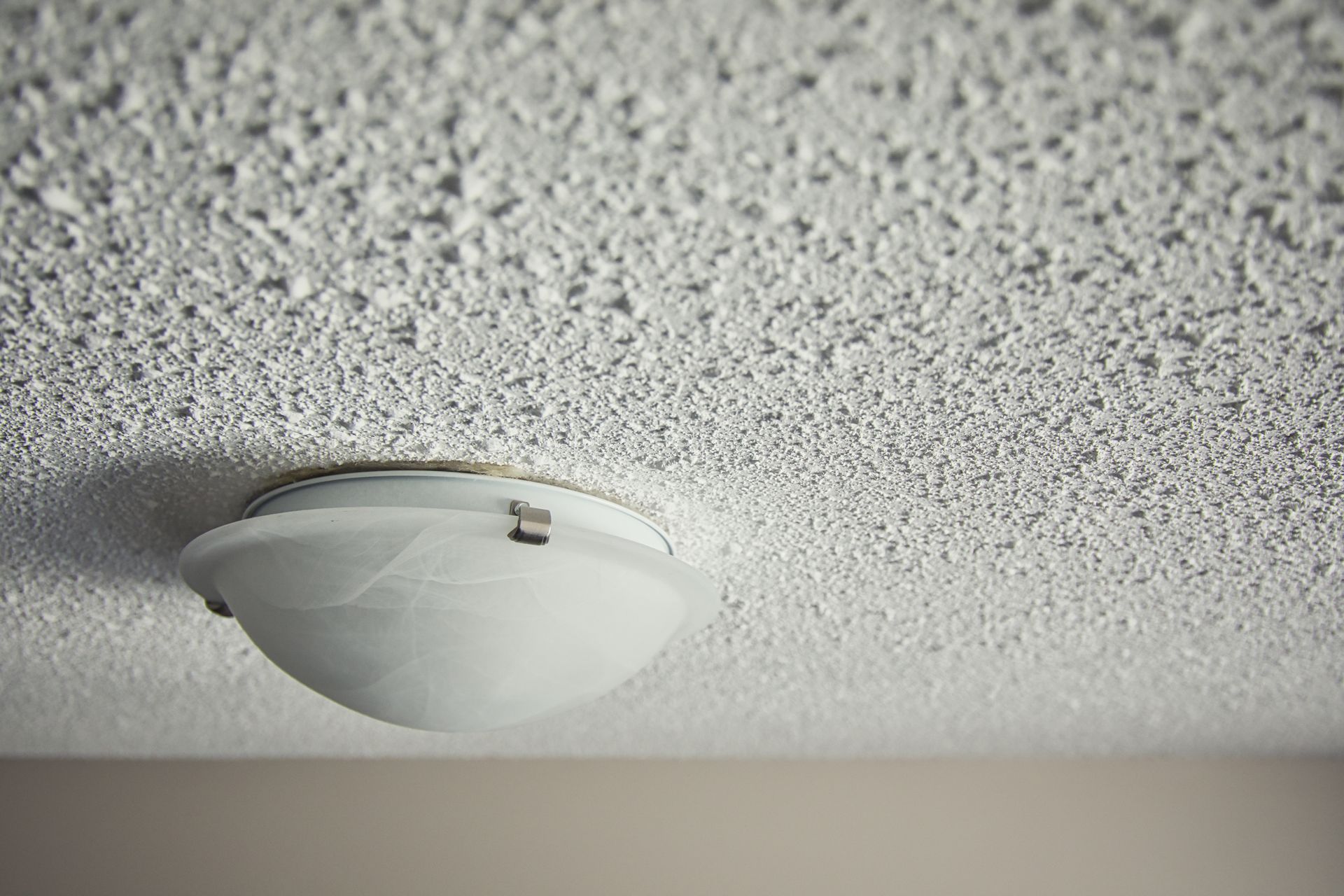 White textured ceiling with a round light fixture.