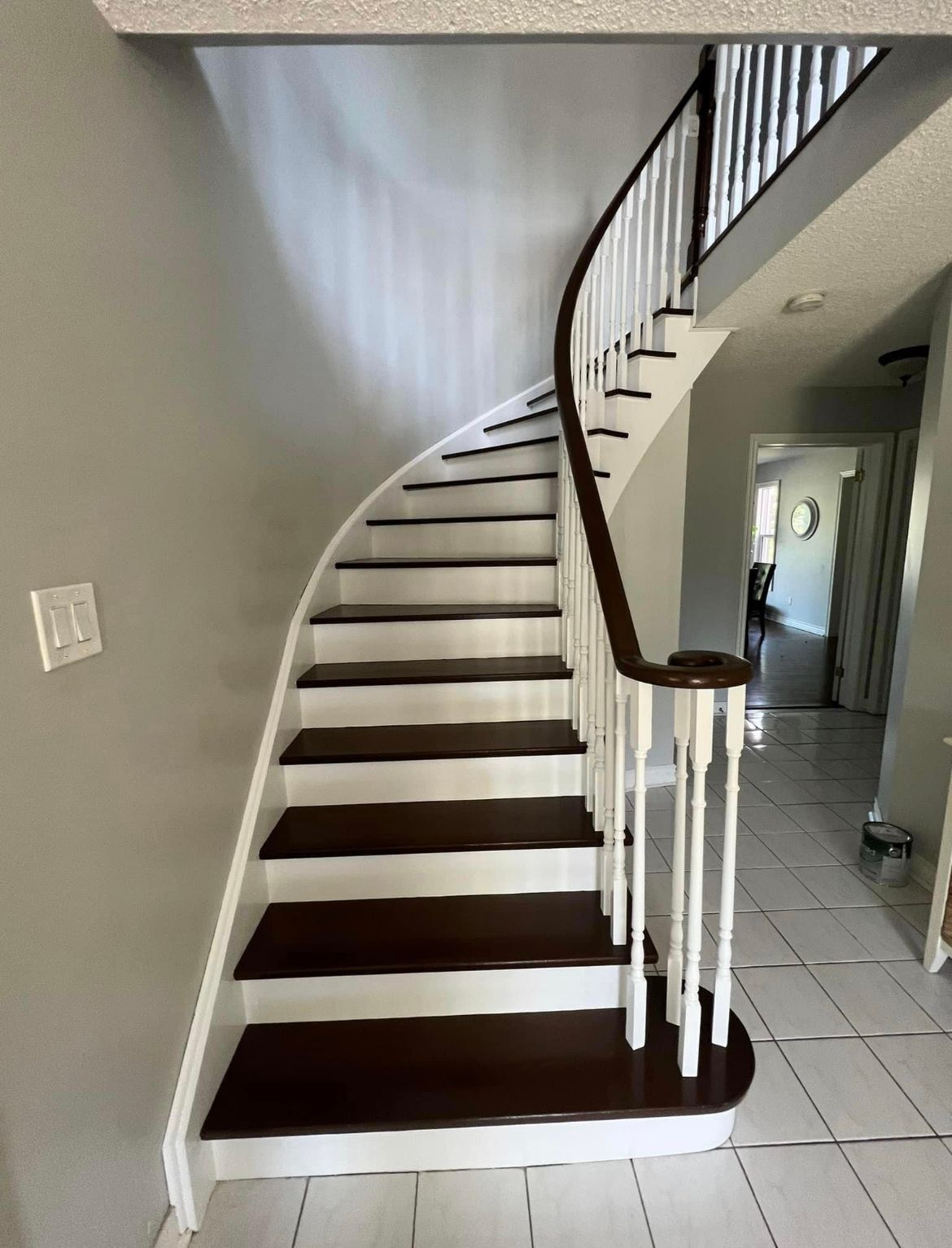 Curved wooden staircase with white accents and a dark wood handrail.