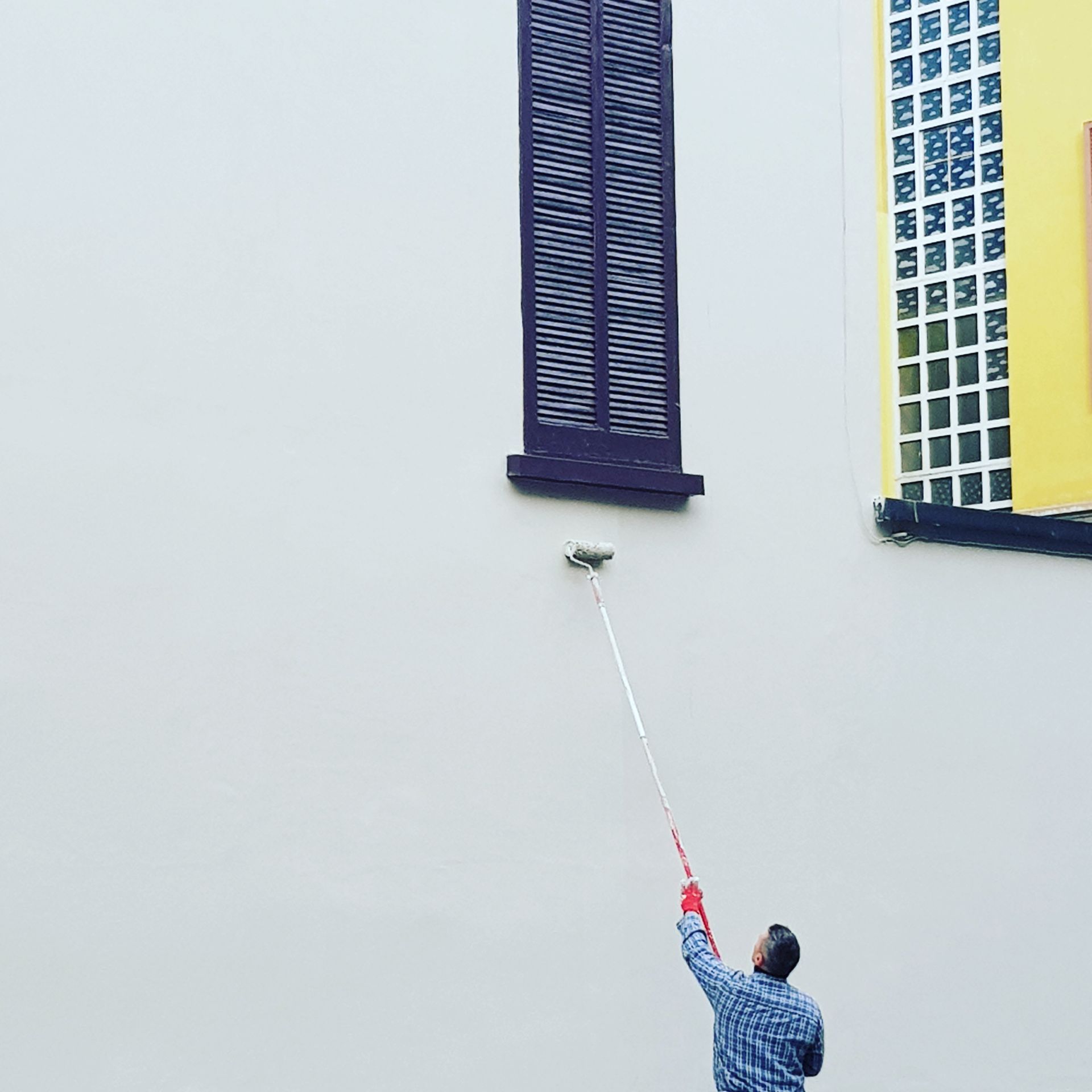 A man is painting a wall with a paint roller