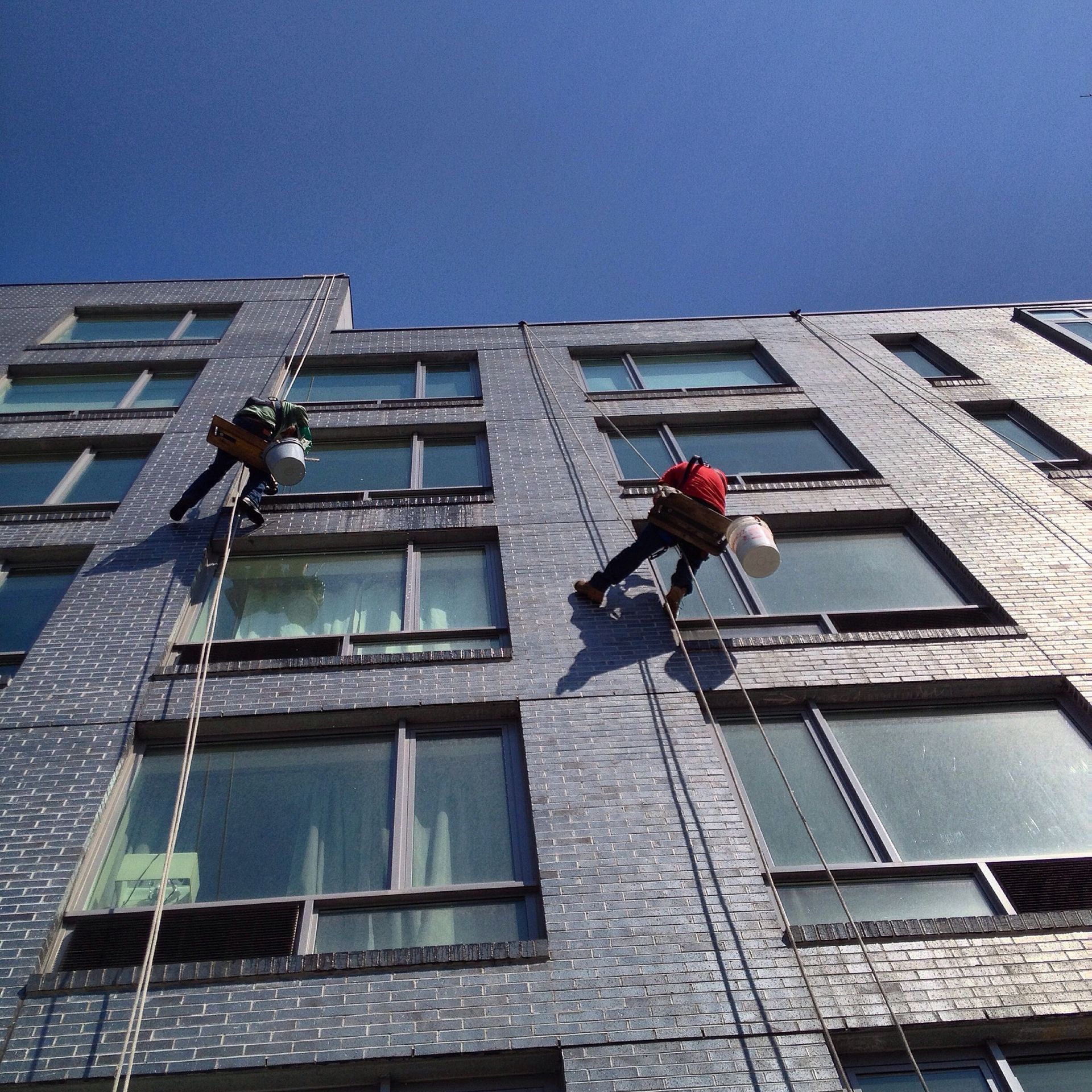 Two men are climbing up the side of a tall building