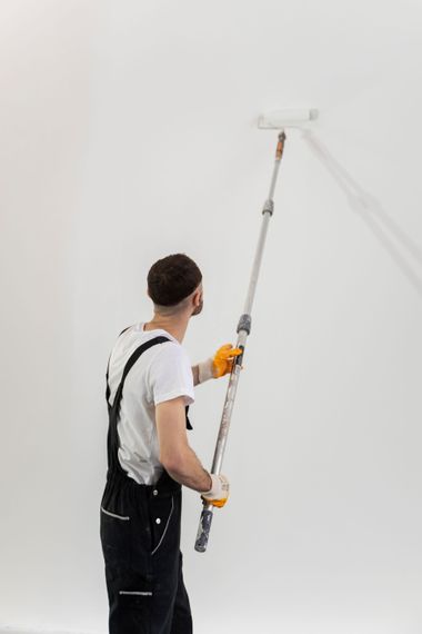 A man is painting a wall with a paint roller.