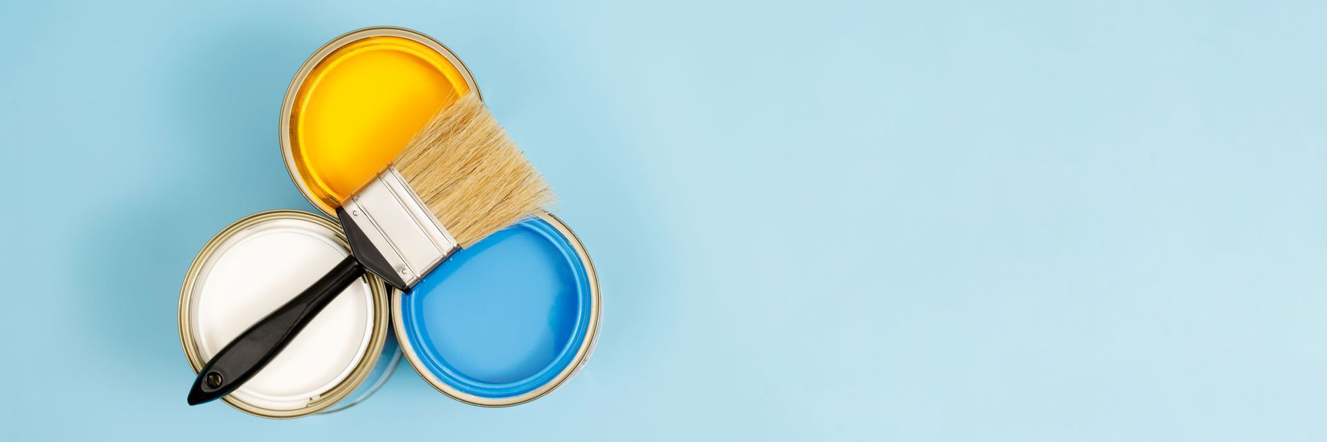 Three cans of paint and a brush on a blue background.