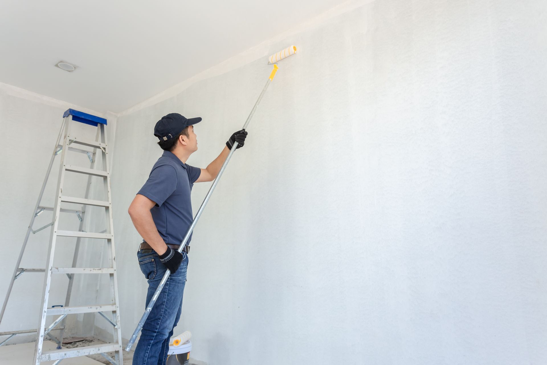 A man is painting a wall with a paint roller.