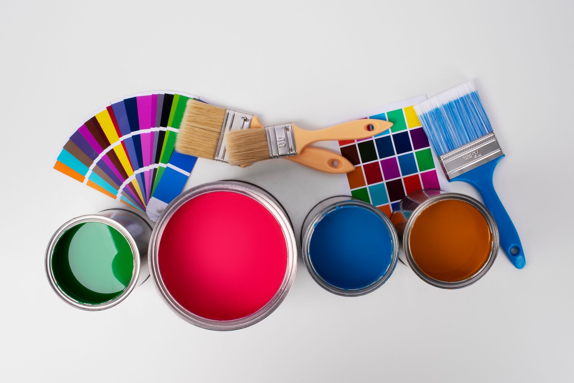 Paint cans in various colors with paintbrushes and color swatches on a white surface.