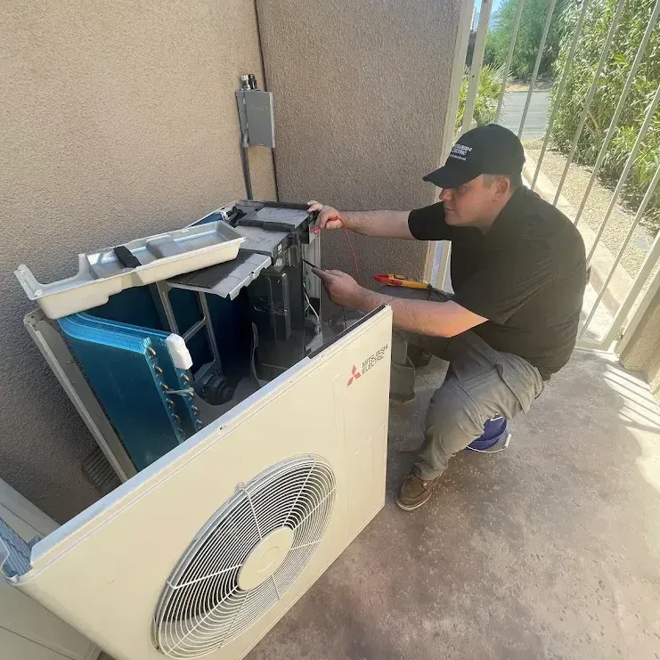 A man is working on an air conditioner on a balcony.