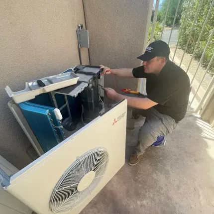 A man is working on an air conditioner on a balcony.