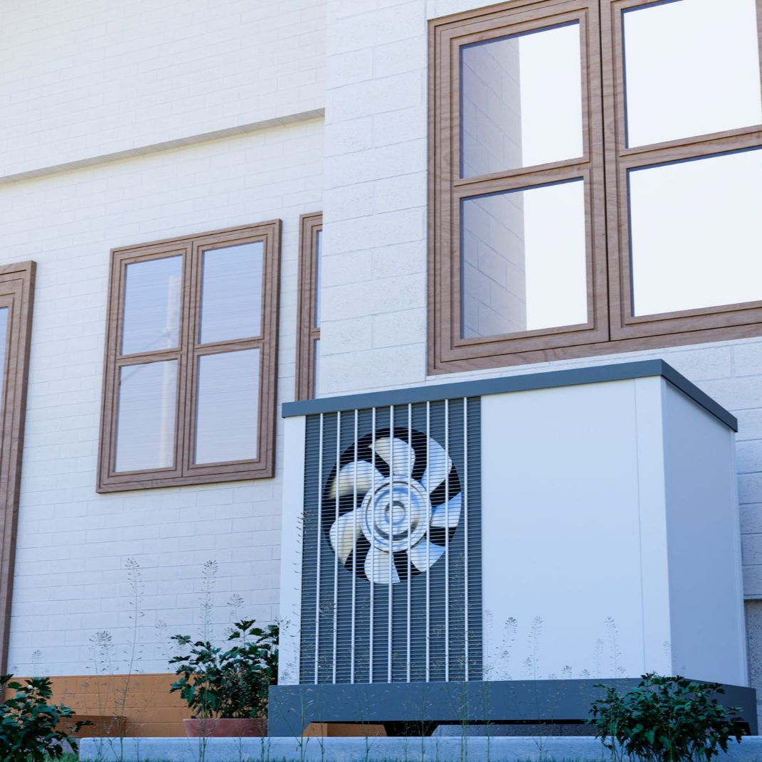 Heat pump unit next to a white brick building with brown-framed windows.