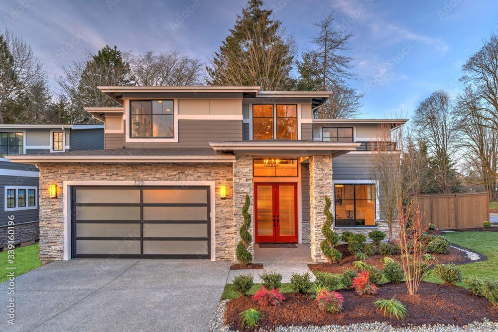 A wide shot of a brick house with a panel by panel glass garage door 
