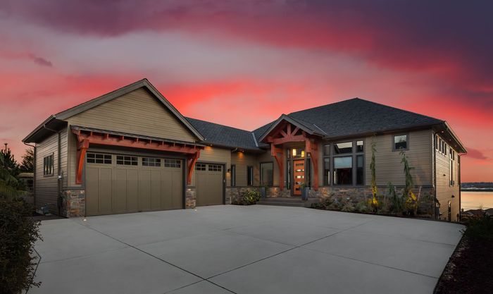 A large house with a large driveway and a sunset in the background.