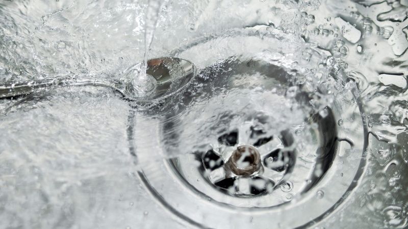 A spoon is sticking out of a sink drain.