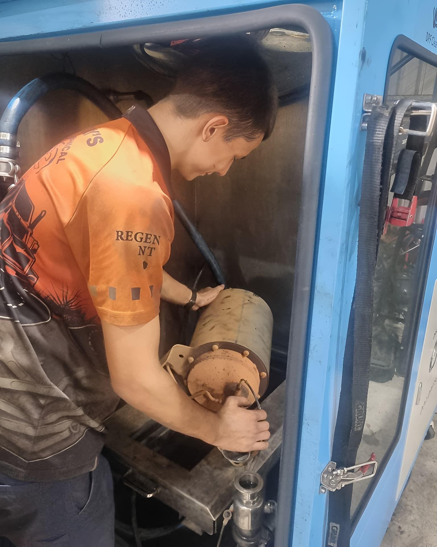 A Man in an Orange Shirt is Working on a Machine — Regen NT In Holtze, NT