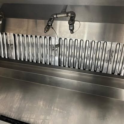A stainless steel exhaust hood with a hose attached to it.