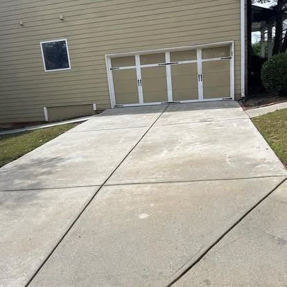 A concrete driveway leading to a garage door of a house.