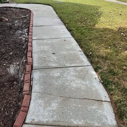 A concrete sidewalk with a brick border and grass on the side.
