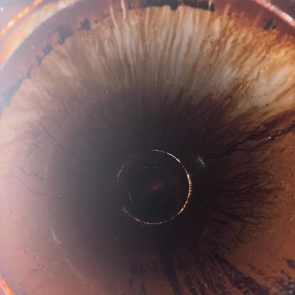 A close up of a rusty pipe with a hole in the middle.