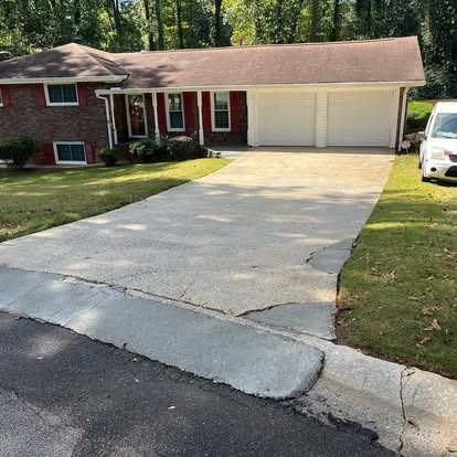 A white car is parked in front of a brick house.