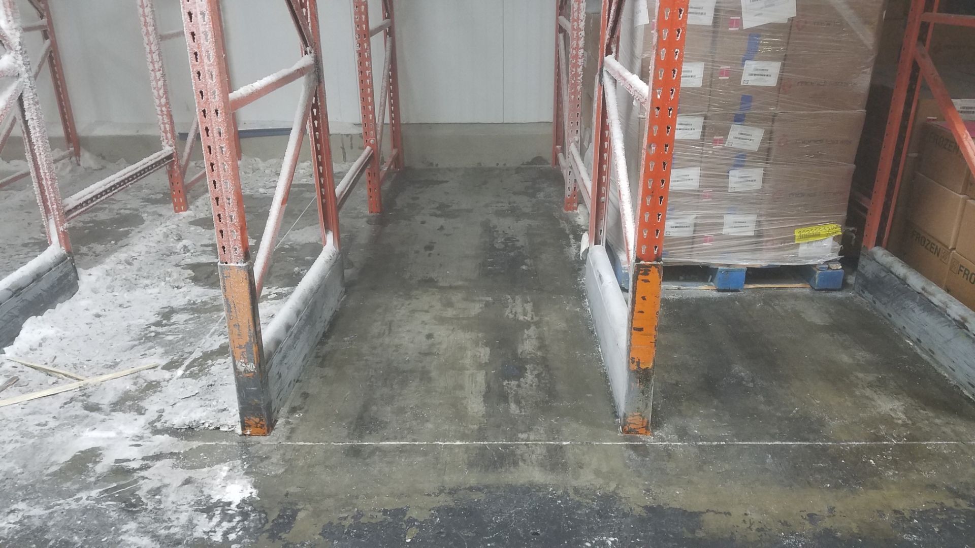 Warehouse interior with metal shelving and concrete floor. Pallet of boxes on the right.