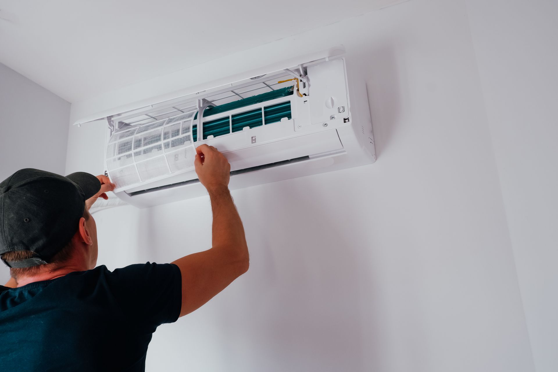 A man is installing an air conditioner on a wall.