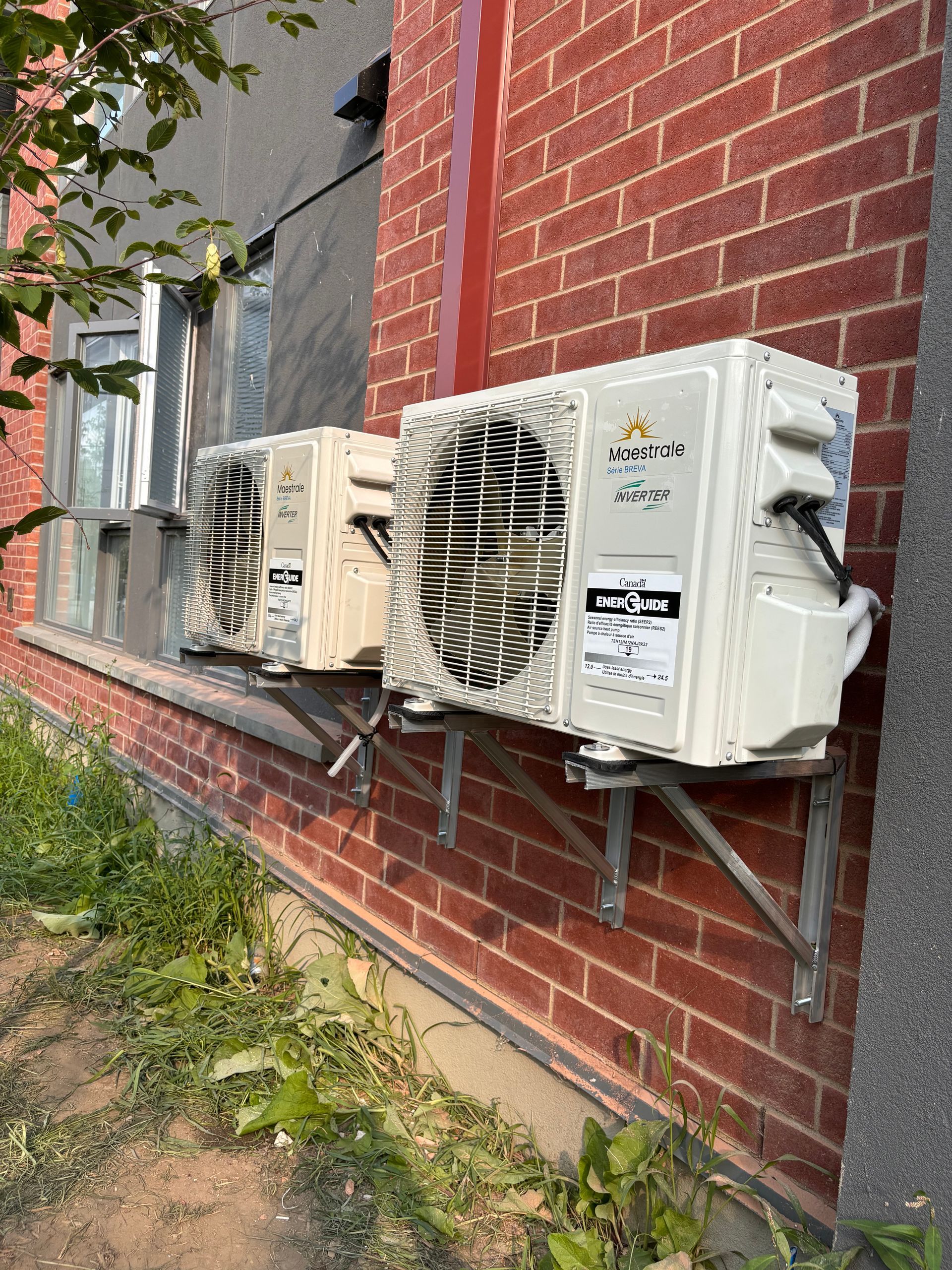 Une rangée de climatiseurs montés sur le côté d'un bâtiment en briques.