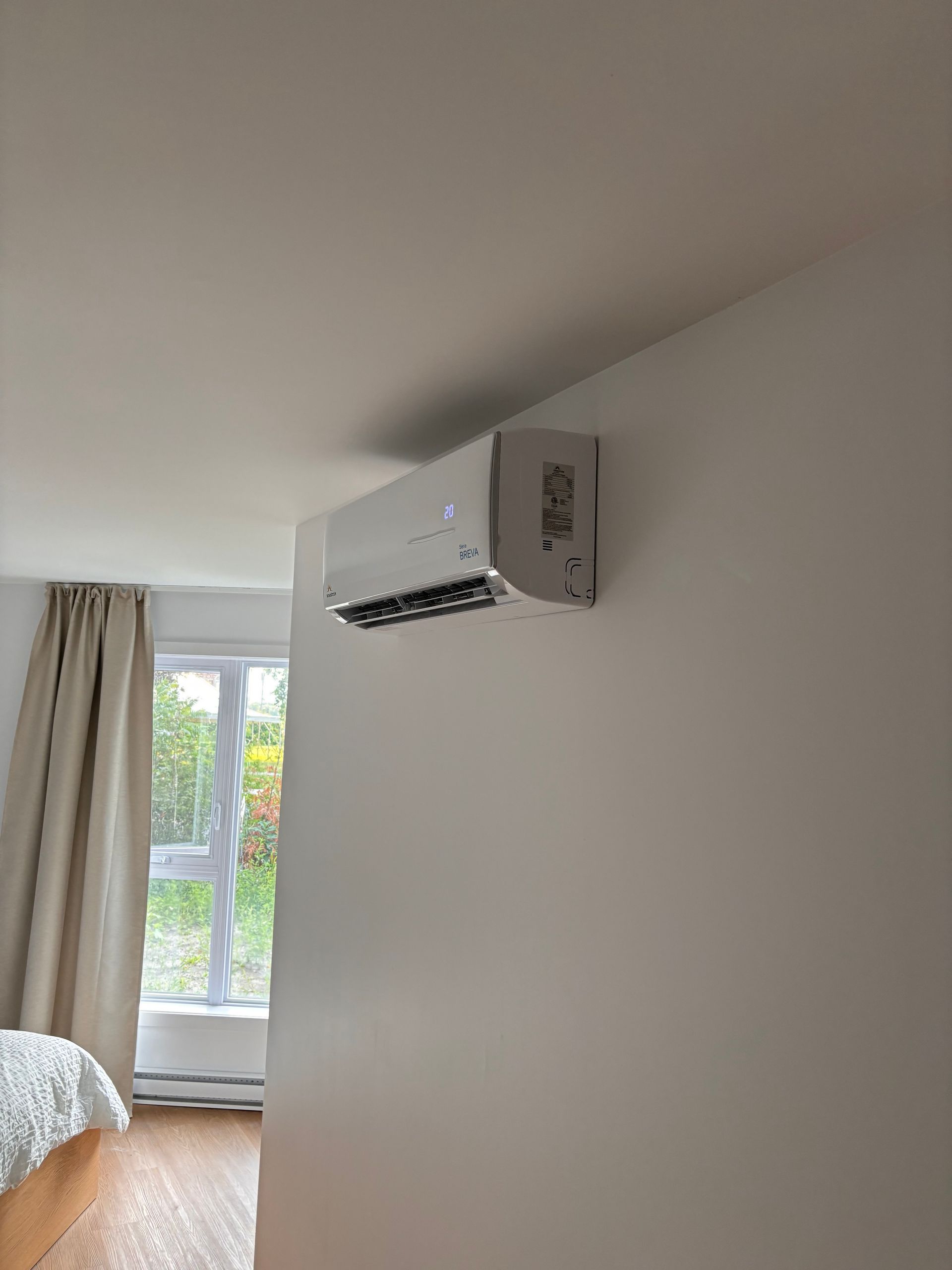 Une chambre avec un lit et une fenêtre avec un climatiseur mural.
