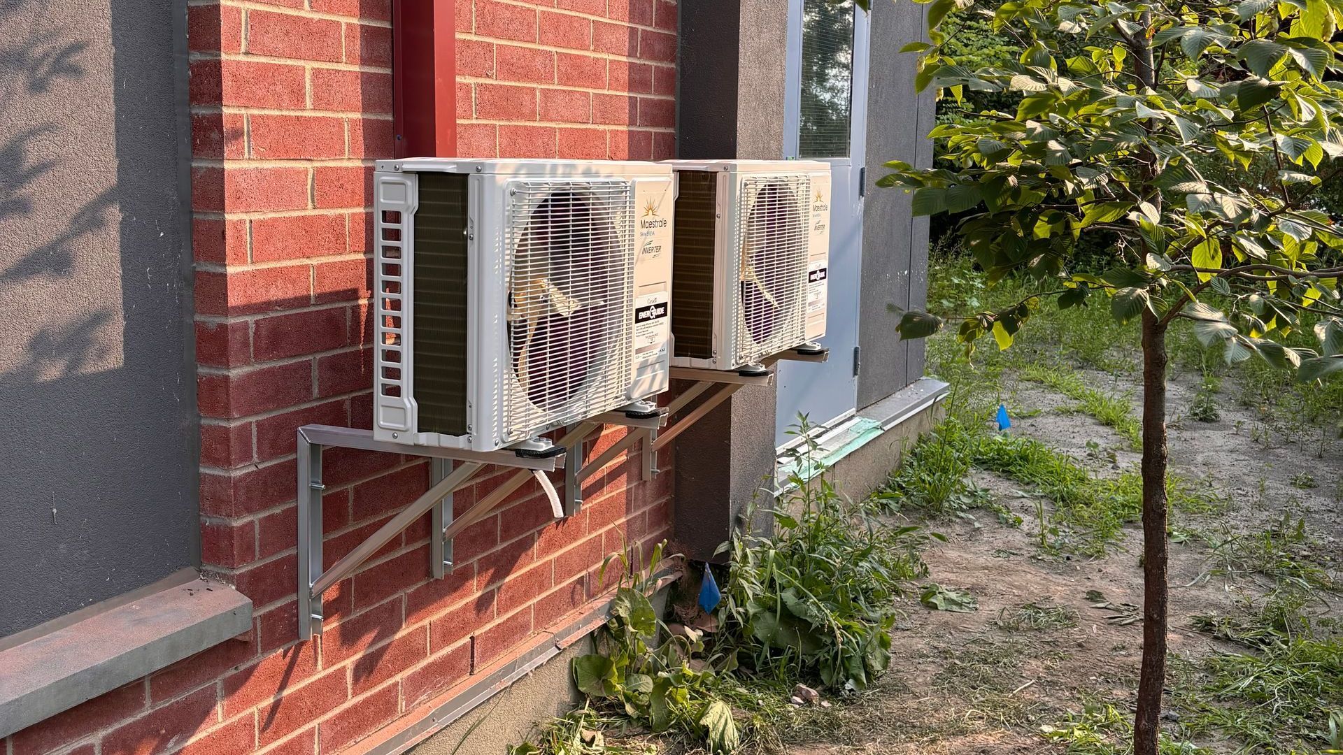 Deux unités de climatisation blanches fixées sur un mur de briques.