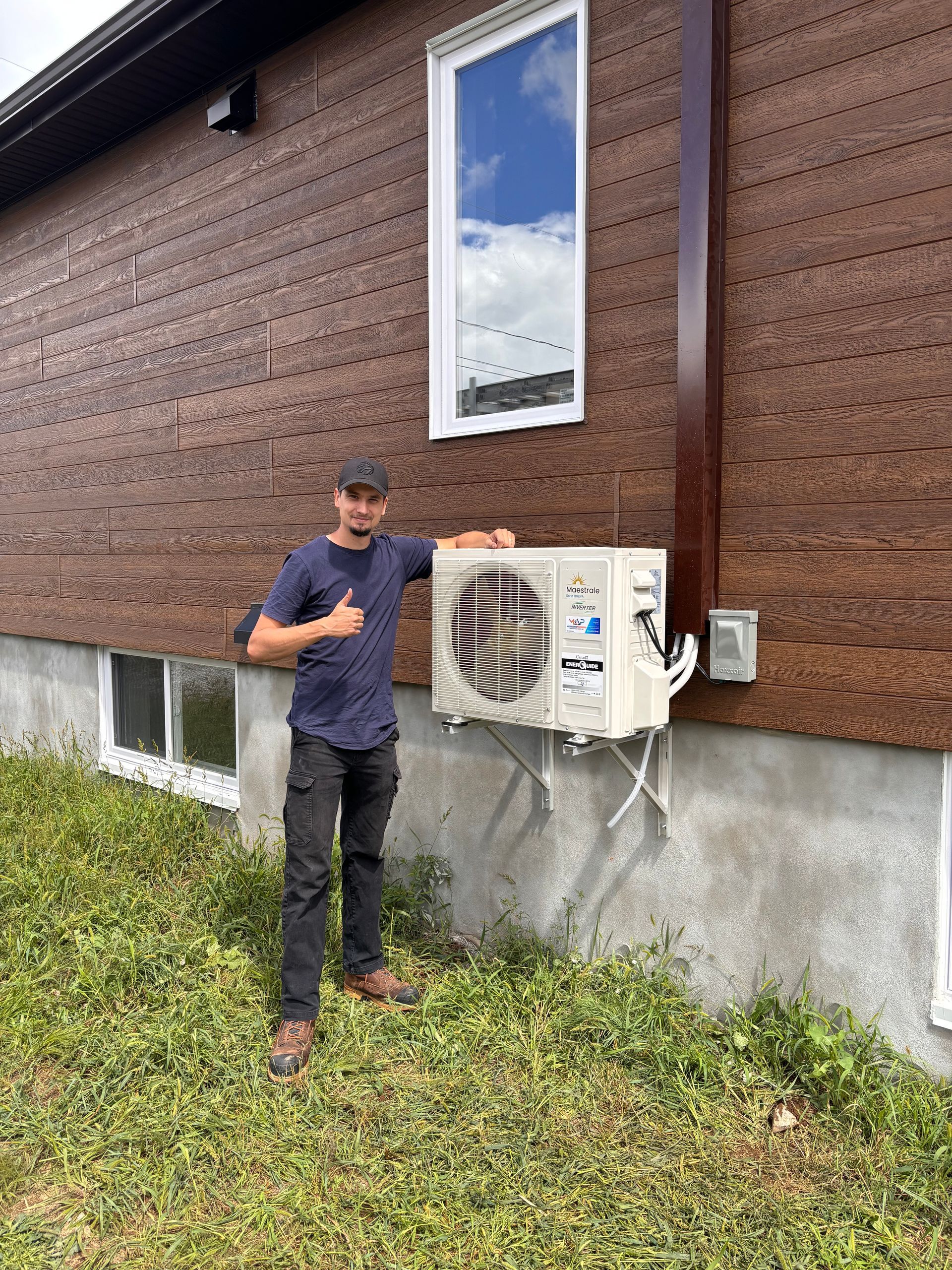 Un homme se tient devant une maison et tient un climatiseur.