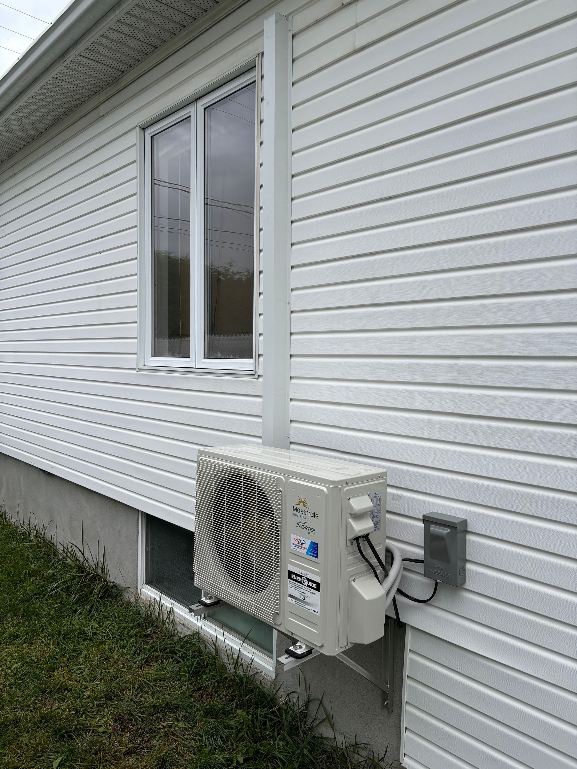Une maison blanche avec une fenêtre et un ventilateur sur le côté.