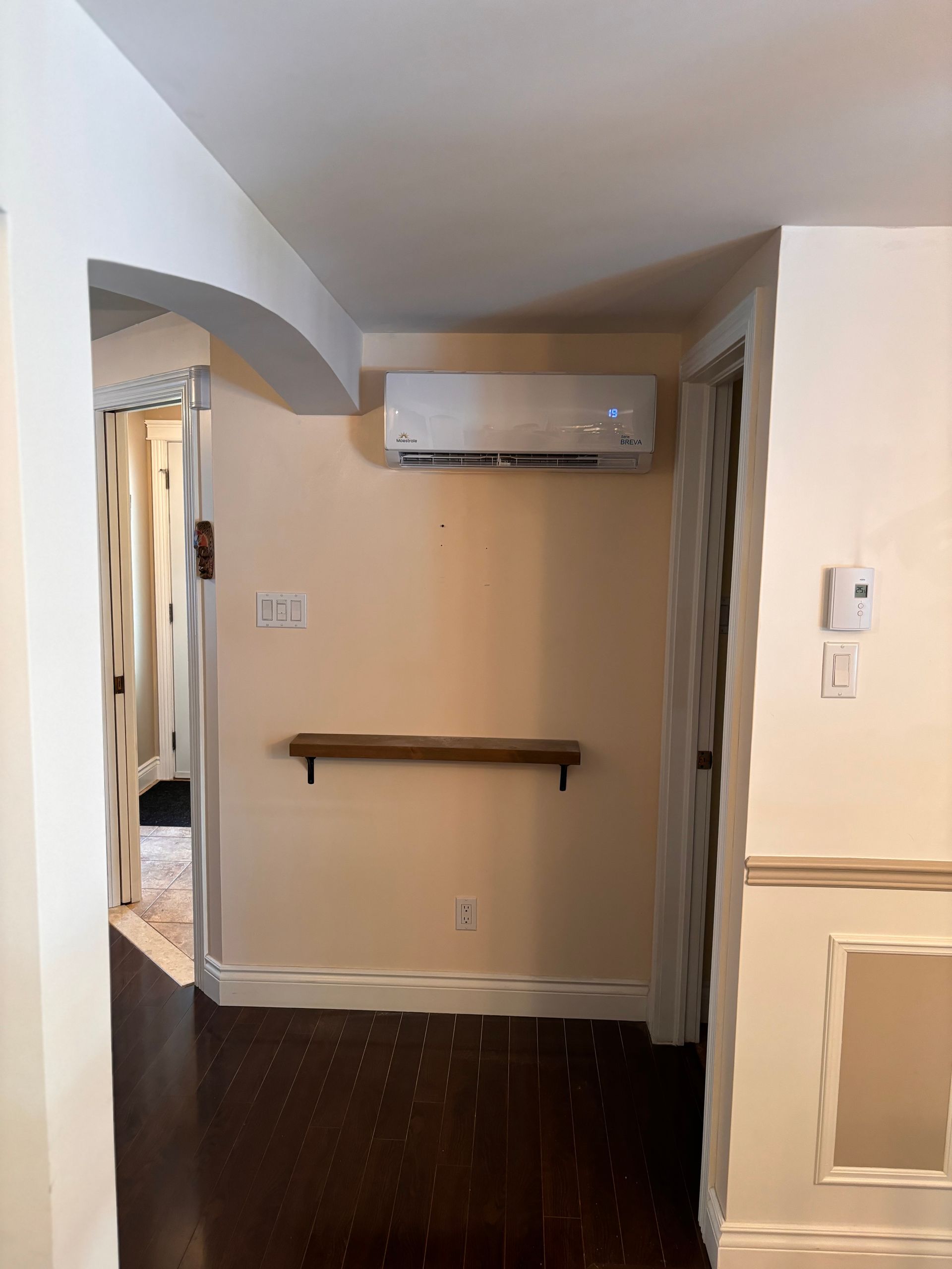 Un couloir avec une étagère et un climatiseur au mur