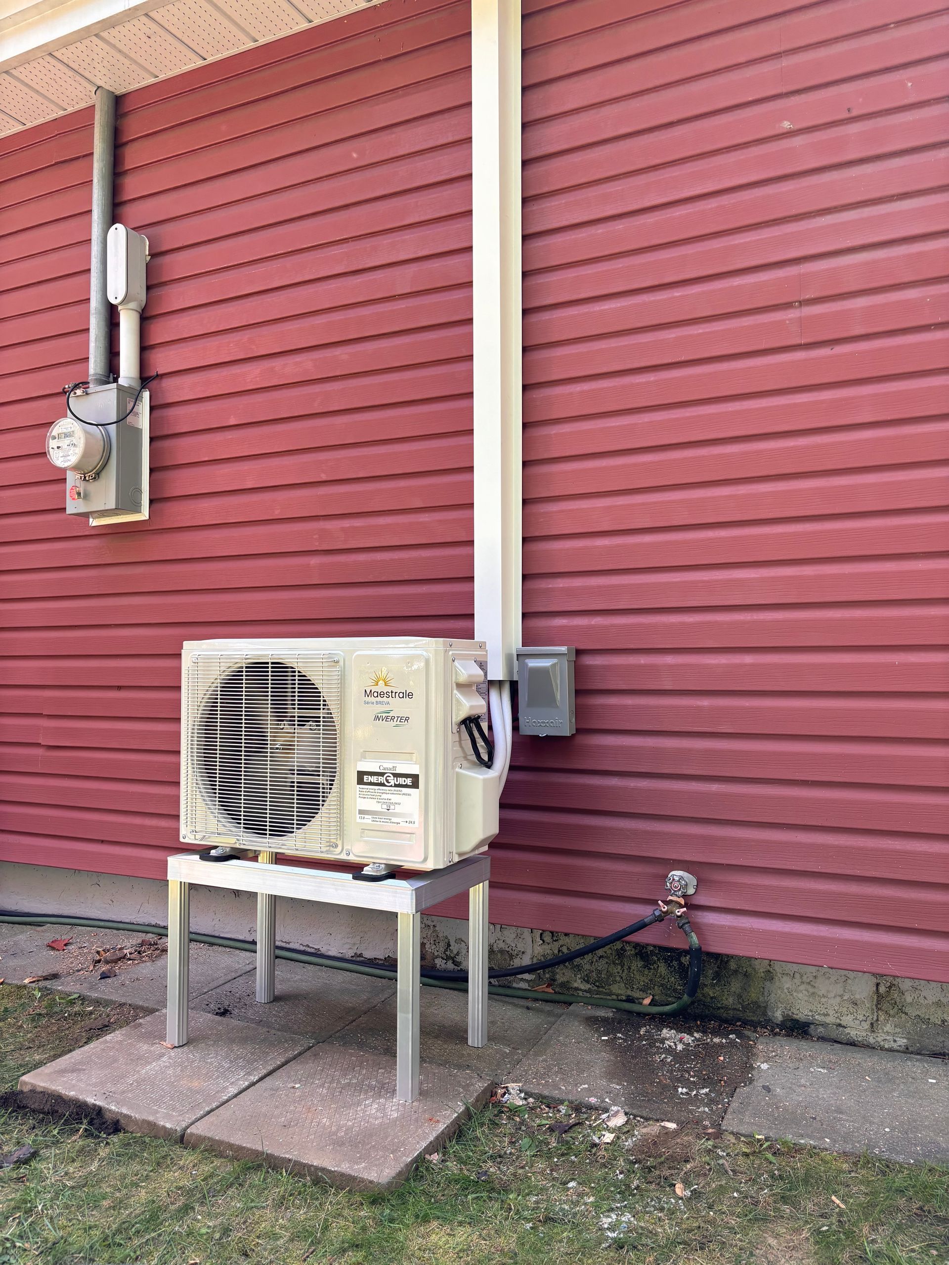 Une maison rouge avec un climatiseur blanc sur le côté.