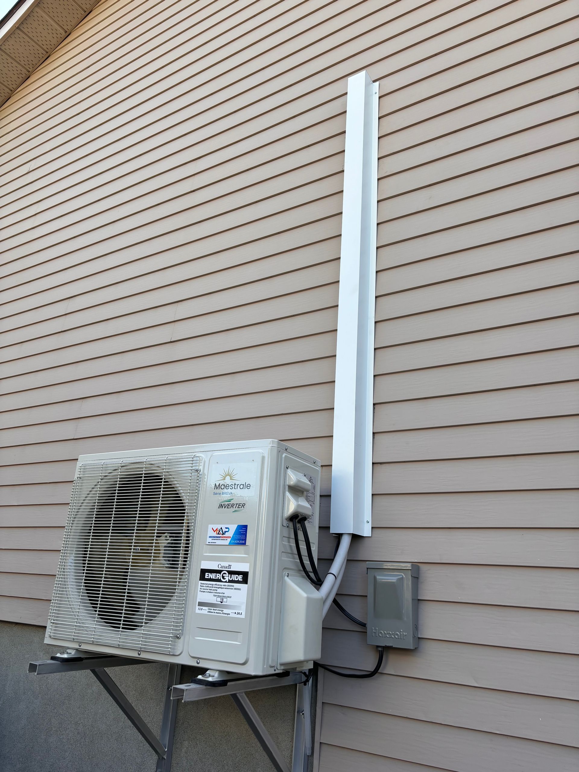 Un climatiseur blanc est monté sur le côté d'une maison.