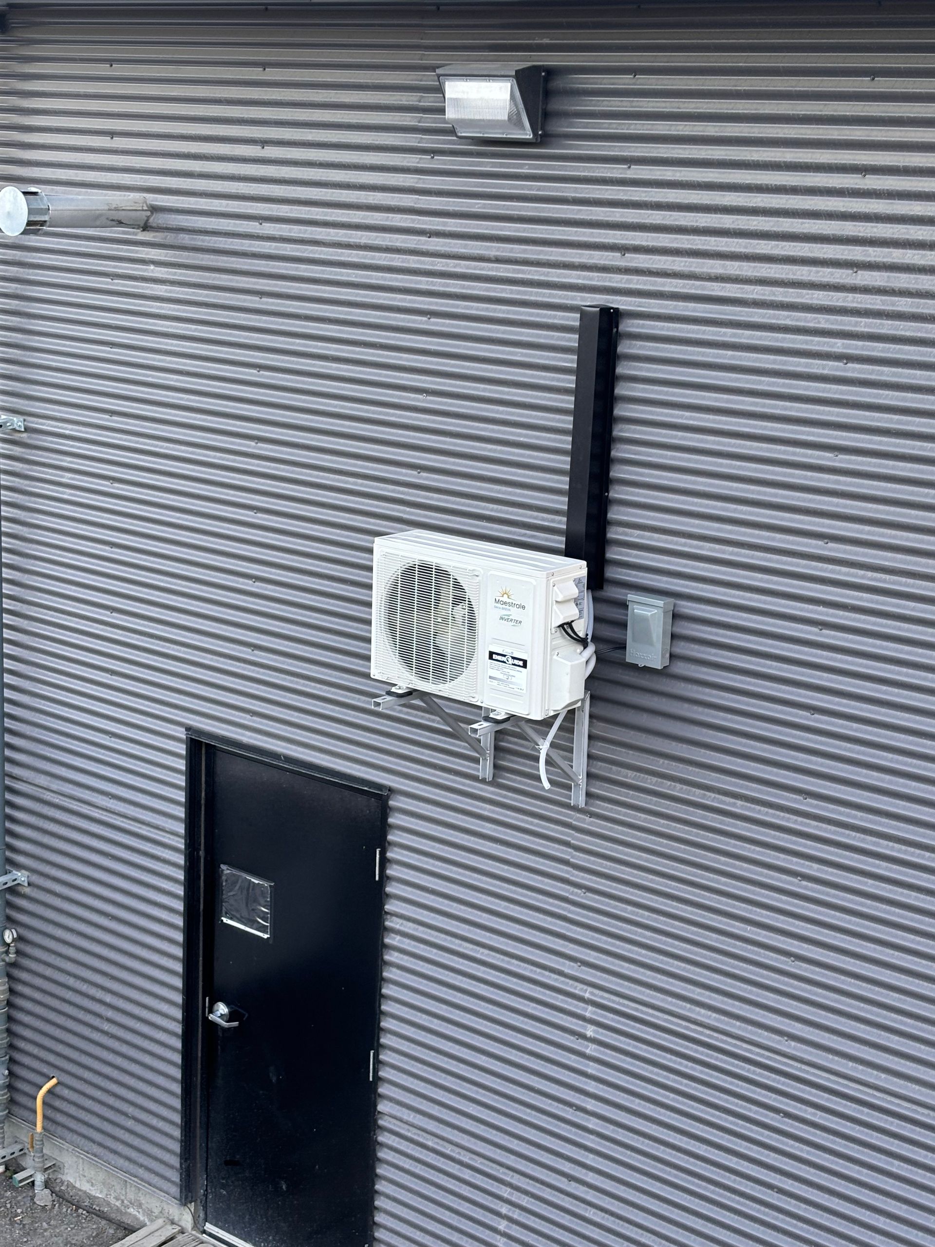 Un climatiseur blanc est monté sur le côté d'un bâtiment à côté d'une porte.