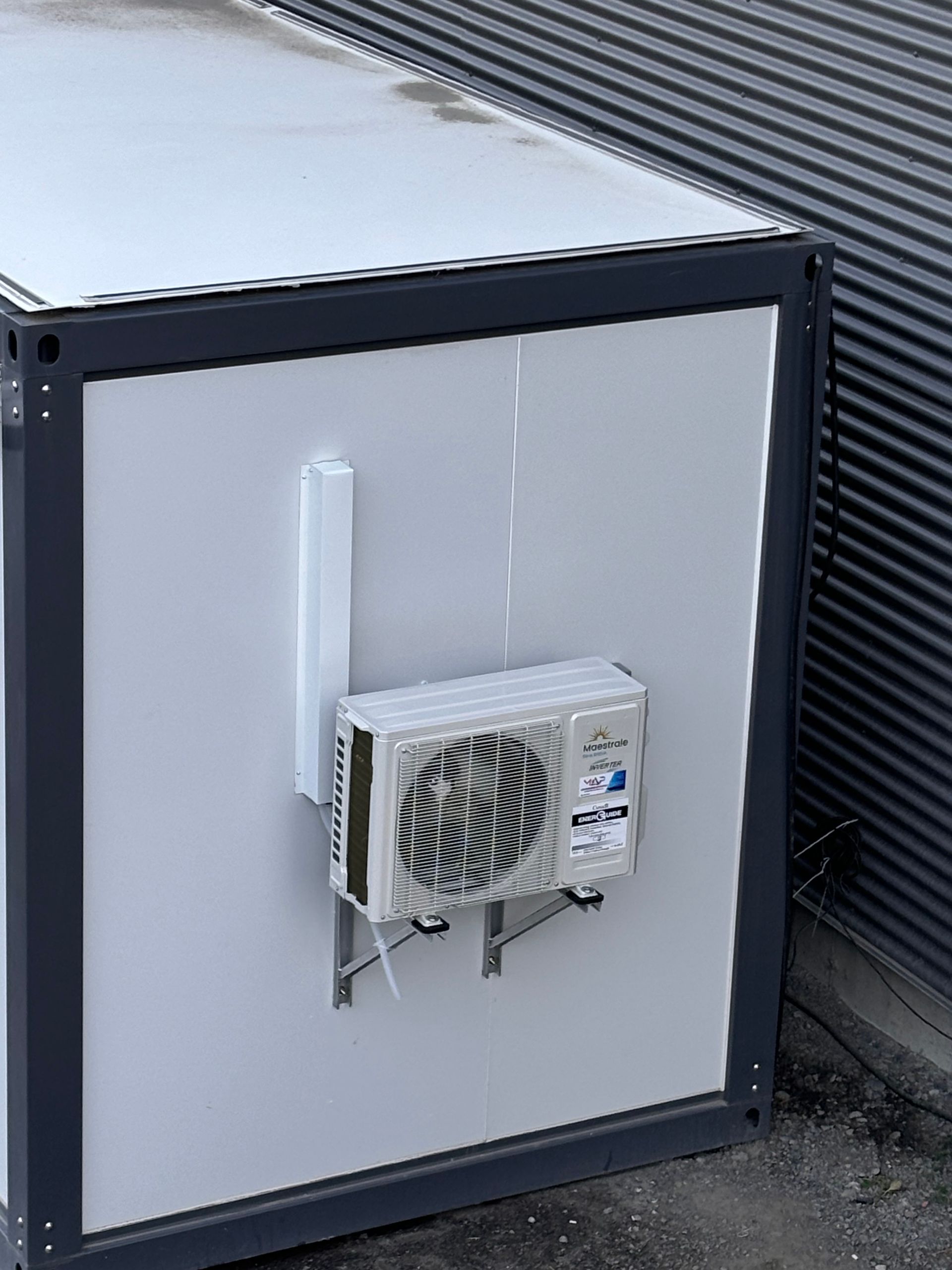 Un petit climatiseur est monté sur le côté d'un bâtiment.